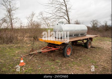 Réservoir d'eau en métal argenté avec pompe à eau à l'avant sur une remorque à l'extérieur à côté d'un champ agricole Banque D'Images