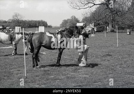 1989, dehors dans un champ, une jeune fille cavalier à côté de son cheval, entrant dans un sac dans le cadre d'une compétition équestre, Angleterre, Royaume-Uni Banque D'Images