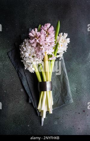 Depuis le haut de la table de printemps avec des fleurs en jacinthe sur une table en béton sombre pour un dîner de fête Banque D'Images