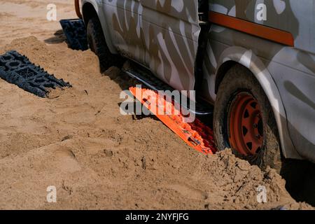 Automobile contemporaine coincée dans un désert sablonneux, debout sur des équipements spéciaux et débardage en Mauritanie Banque D'Images