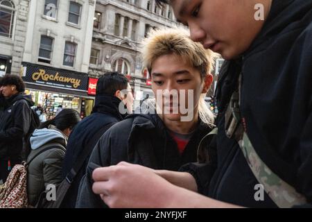 Deux hommes asiatiques utilisent un téléphone portable pour obtenir des informations en ville. Londres, Royaume-Uni Banque D'Images