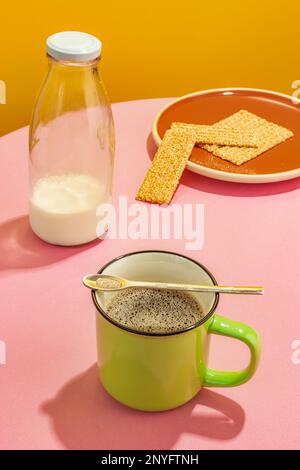 Bouteille de lait en verre et tasse de café aromatique sur table rose sur fond jaune Banque D'Images