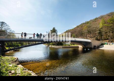 Touristes marchant sur le nouveau pont sur la rivière Eamont profitant du soleil à Pooley Bridge Ullswater le Lake District, Cumbria Banque D'Images