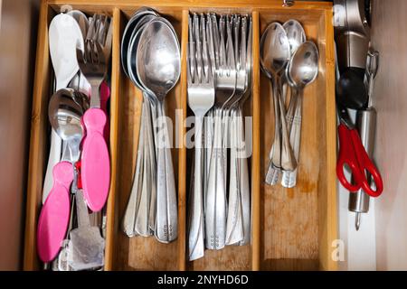 Cuillères propres et argentées, fourchettes au tiroir de cuisine avec set de couverts. Vue à plat du plateau de rangement avec kit simple d'ustensiles dans une boîte de rangement ouverte. Banque D'Images