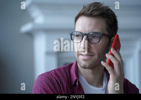 Gros plan portrait d'un jeune homme d'affaires allemand confiant et réfléchi en lunettes ayant une conversation urgente sur téléphone portable avec le bureau principal de la société ou c Banque D'Images