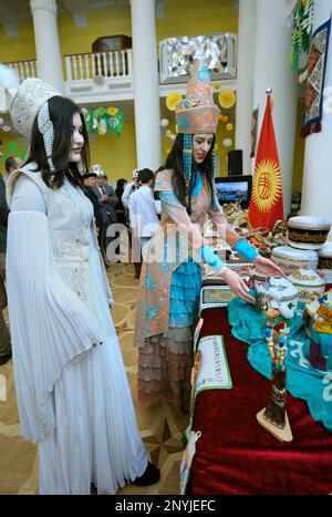 Jeunes femmes asiatiques vêtues de costumes nationaux kirghizes présentant un stand du Kirghizistan. Festival de la culture orientale. Banque D'Images