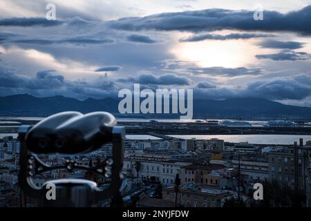Vue panoramique de Cagliari au coucher du soleil depuis Buoncammino avec des jumelles floues pour les touristes Banque D'Images