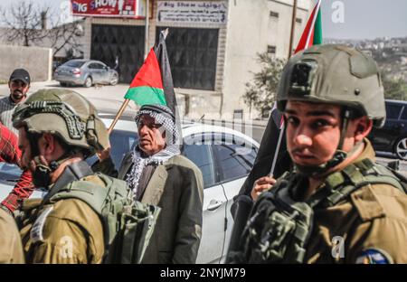 Naplouse, Palestine. 02nd mars 2023. Un homme palestinien âgé fait passer le drapeau palestinien devant les soldats israéliens lors d'une protestation contre les attaques des colons juifs et la fermeture des magasins commerciaux par l'armée israélienne dans la ville de Hawara, au sud de Naplouse, en Cisjordanie occupée. Crédit : SOPA Images Limited/Alamy Live News Banque D'Images