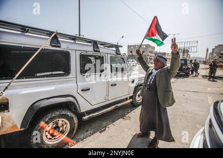 Naplouse, Palestine. 02nd mars 2023. Un palestinien âgé fait passer le drapeau palestinien devant une jeep militaire israélienne lors d'une protestation contre les attaques des colons juifs et la fermeture des magasins commerciaux par l'armée israélienne dans la ville de Hawara, au sud de Naplouse, en Cisjordanie occupée. Crédit : SOPA Images Limited/Alamy Live News Banque D'Images