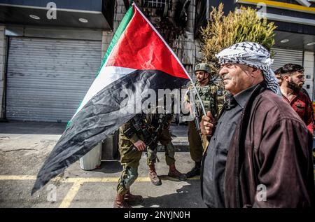 Naplouse, Palestine. 02nd mars 2023. Un homme palestinien âgé fait passer le drapeau palestinien devant les soldats israéliens lors d'une protestation contre les attaques des colons juifs et la fermeture des magasins commerciaux par l'armée israélienne dans la ville de Hawara, au sud de Naplouse, en Cisjordanie occupée. Crédit : SOPA Images Limited/Alamy Live News Banque D'Images