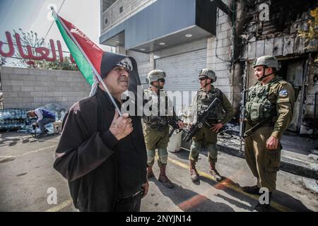 Naplouse, Palestine. 02nd mars 2023. Un homme palestinien âgé fait passer le drapeau palestinien devant les soldats israéliens lors d'une protestation contre les attaques des colons juifs et la fermeture des magasins commerciaux par l'armée israélienne dans la ville de Hawara, au sud de Naplouse, en Cisjordanie occupée. Crédit : SOPA Images Limited/Alamy Live News Banque D'Images