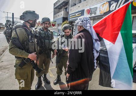 Naplouse, Palestine. 02nd mars 2023. Un palestinien âgé défend avec les soldats israéliens tout en levant le drapeau palestinien lors d'une protestation contre les attaques des colons juifs et la fermeture des magasins commerciaux par l'armée israélienne dans la ville de Hawara, au sud de Naplouse, en Cisjordanie occupée. (Photo de Nasser Ishtayeh/SOPA Images/Sipa USA) crédit: SIPA USA/Alay Live News Banque D'Images