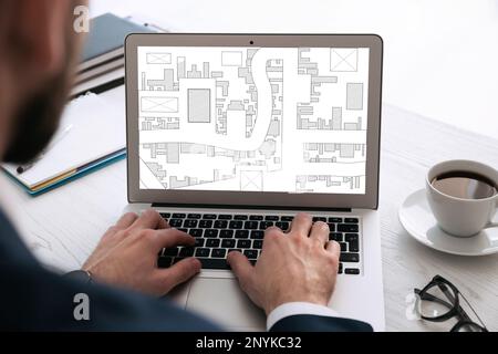 Homme analysant la carte cadastrale sur ordinateur portable à la table, gros plan Banque D'Images