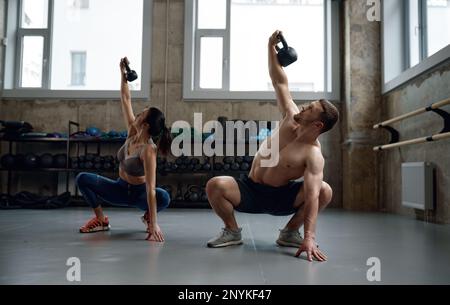 Homme et femme avec un bon physique tenant une lourde cloche de bouilloire Banque D'Images