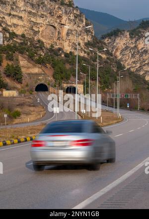 Voiture avec flou de mouvement conduite sur autoroute vers le tunnel sous la colline. Banque D'Images