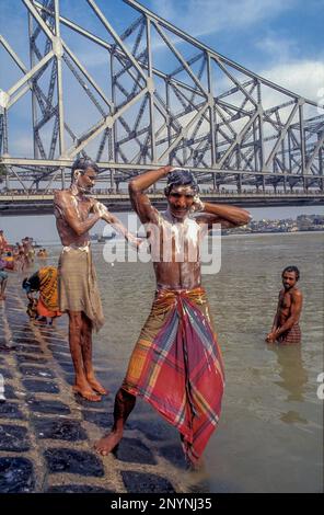 Inde, Calcutta ou Kolkata. Des hommes prenant un bain dans la rivière Hooghly près du pont Howrah. Banque D'Images