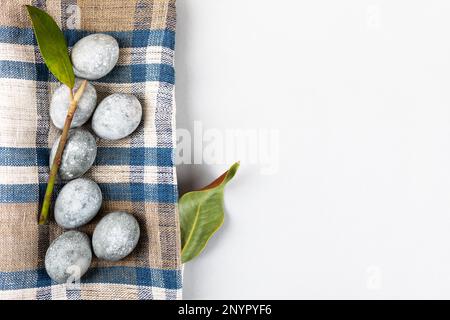 Œufs de Pâques gris avec une branche et une feuille de magnolia sur fond gris. Minimalisme, espace de copie, pose à plat Banque D'Images