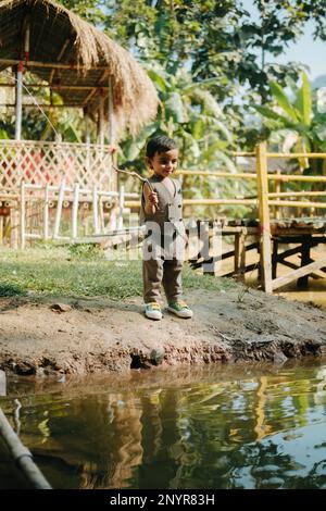 Un enfant pêche dans un étang, Guwahati, Assam Banque D'Images