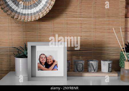 Cadre avec photo d'une femme âgée et de sa petite-fille sur une table blanche à l'intérieur Banque D'Images