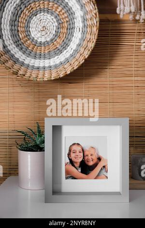 Cadre avec photo d'une femme âgée et de sa petite-fille sur une table blanche à l'intérieur Banque D'Images