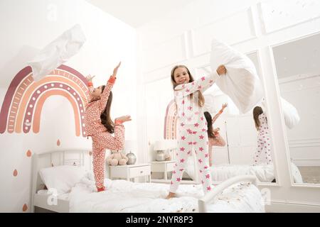 Jolies petites filles en pyjama jouant sur le lit à la maison. Bonne enfance Banque D'Images