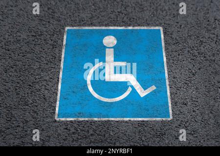 Symbole fauteuil roulant sur la route asphaltée, vue au-dessus. Permis de stationnement pour personnes handicapées Banque D'Images