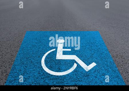 Symbole fauteuil roulant sur la route asphaltée. Permis de stationnement pour personnes handicapées Banque D'Images