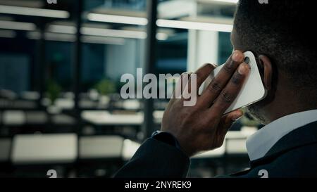 Vue arrière african Ethnic entrepreneurs employeur PDG patron homme parlant téléphone mobile intérieur bureau distant conversation d'affaires à l'aide de la technologie moderne Banque D'Images