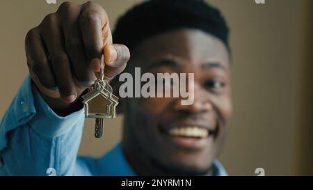 Heureux propriétaire d'une maison afro-américaine ethnique homme d'affaires 30s agent immobilier employé de bureau propriétaire montrant les clés de la nouvelle maison à l'achat de caméra maison Banque D'Images