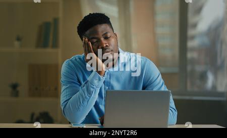 Ennuyé homme d'affaires épuisé africain américain employé Manager adulte homme ethnique dormir bureau sieste au bureau paresseux travailleur réveil répondre mobile Banque D'Images