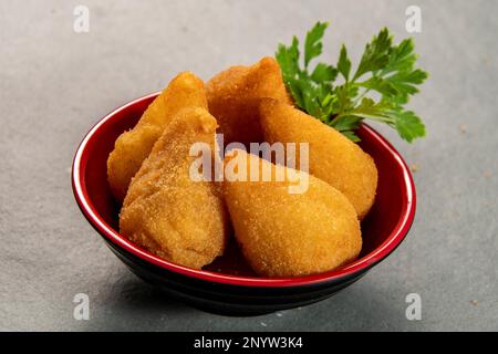 coxinha frit traditionnel dans une assiette sur fond d'ardoise, en-cas brésilien populaire servi lors de fêtes Banque D'Images