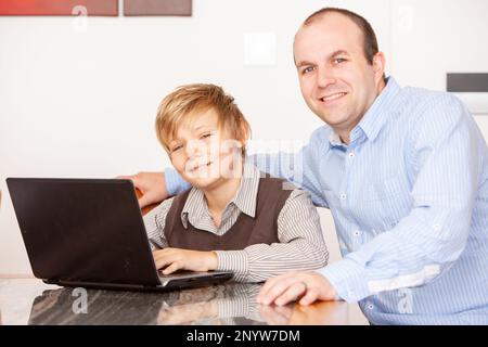 Vie de famille, travailler ensemble. Un père et un fils collaborent ensemble sur un projet scolaire à l'aide d'un ordinateur portable. À partir d'une série d'images associées. Banque D'Images