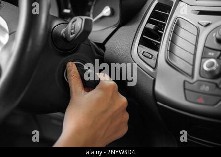 La main d'une femme démarre la voiture avec une clé. Banque D'Images