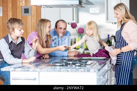 Vie de famille, biscuits au four. Une famille se réunit dans la cuisine pour déguster les petits gâteaux frais de maman. À partir d'une série d'images associées. Banque D'Images