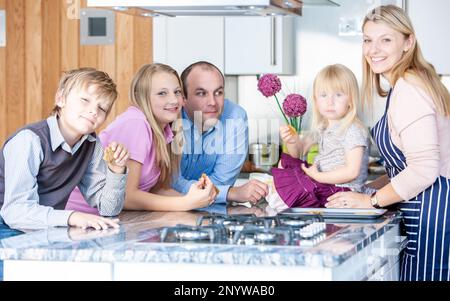 Vie de famille, petits gâteaux faits maison. Une famille se réunit dans la cuisine pour déguster des friandises fraîchement préparées de la part de sa mère. À partir d'une série d'images associées. Banque D'Images