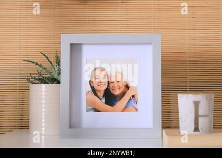 Cadre avec photo d'une femme âgée et de sa petite-fille sur une table blanche à l'intérieur Banque D'Images