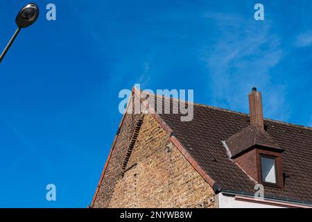Partie d'un toit carrelé avec une fenêtre de dormeur et une cheminée. Feu de route sous ciel bleu. Banque D'Images