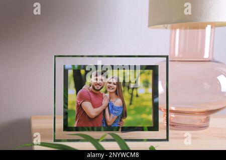 Cadre avec photo de jeune couple sur table en bois à l'intérieur Banque D'Images