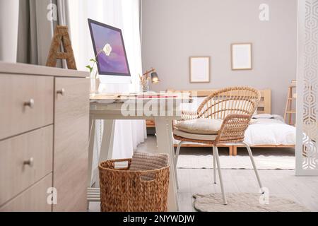 Espace de travail confortable avec ordinateur moderne près de la fenêtre dans la chambre. Design intérieur Banque D'Images