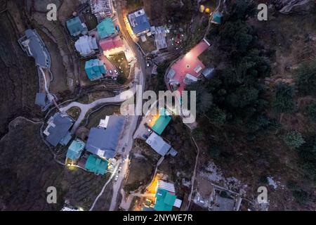 un drone aérien a tiré dessus en bas de la vue de la circulation dans les routes étroites sinueuses de colline avec des lumières éclairant sur les voitures et les bâtiments tournés à manali shimla himachal Banque D'Images