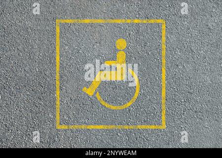 Symbole fauteuil roulant sur la route asphaltée, vue de dessus. Permis de stationnement pour personnes handicapées Banque D'Images