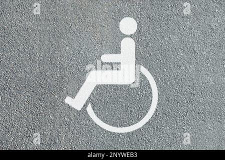 Symbole fauteuil roulant sur la route asphaltée, vue de dessus. Permis de stationnement pour personnes handicapées Banque D'Images