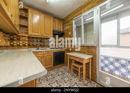 Cuisine meublée de mobilier en bois de style castillan, table pliante d'un côté, carrelage vintage saisissant sur les sols et les murs et sortie vers une terrasse Banque D'Images