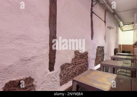 Hall allongé d'un restaurant vide avec tables en métal de style industriel, murs avec plâtrage asymétrique, briques apparentes et poutres en bois Banque D'Images