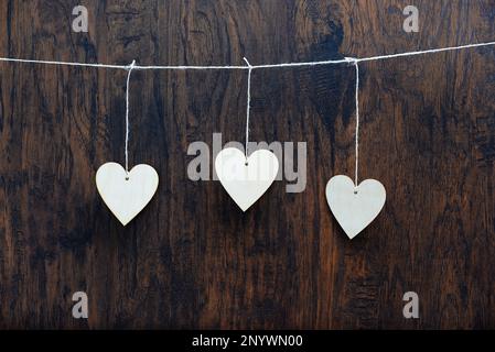 Coeur en contreplaqué suspendu sur la corde à linge. Sur un arrière-plan en bois ancien. Banque D'Images