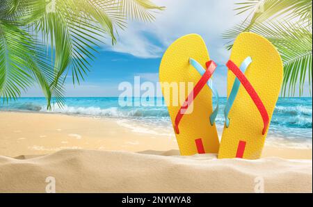 Tongs jaunes sur la plage de sable près de la mer Banque D'Images