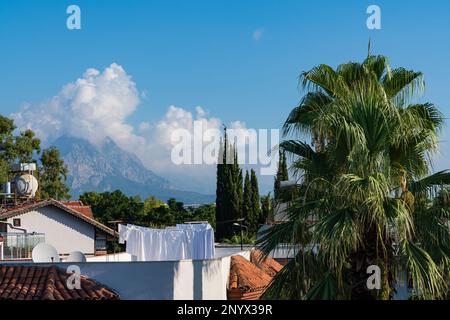 Draps blancs suspendus pour le soleil sèche sur le toit d'une maison en Turquie. Palmiers et montagnes sous le ciel bleu. Banque D'Images