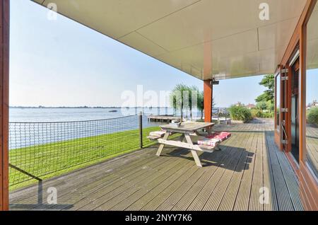 une terrasse avec des chaises et des tables surplombant l'eau lors d'une journée ensoleillée dans cette photo est prise d'un salon extérieur Banque D'Images