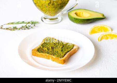 griller avec de l'avocat et de la sauce chimichurri sur une assiette blanche. Nourriture végétarienne saine. Arrière-plan blanc. Banque D'Images