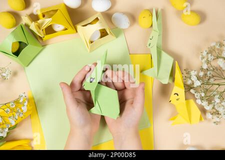 Artisanat du papier pour Pâques - origami, faisant des figurines de lapins de Pâques, les mains d'enfants gros plan Banque D'Images